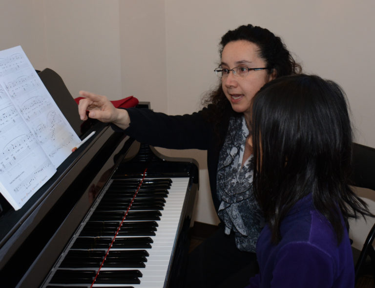 Elementary-aged student at the piano with a supportive music teacher, turning a learning moment into growth during a music lesson